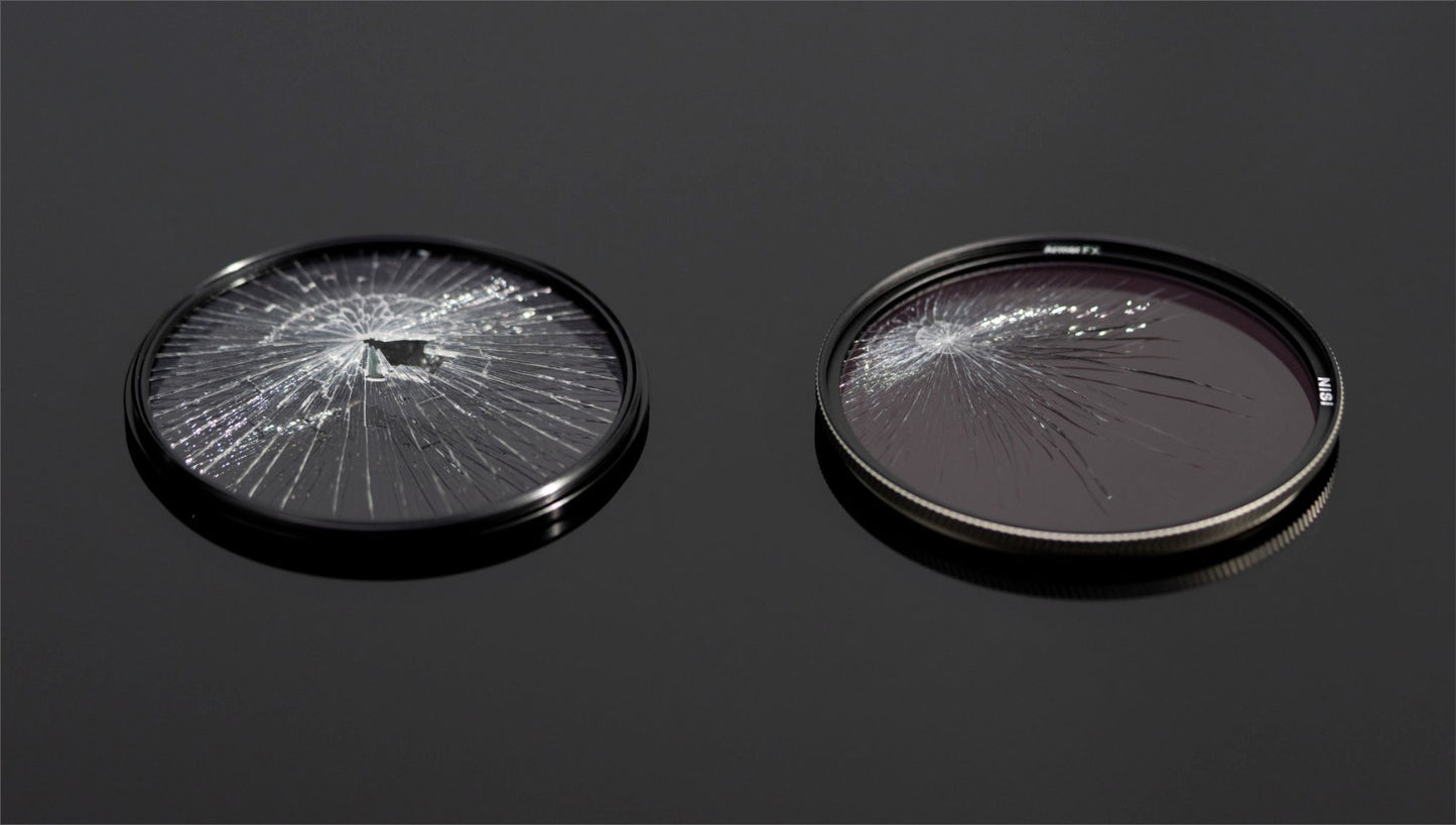 Damaged NiSi Armor FX UV filter displaying cracks alongside an undamaged filter on a reflective surface