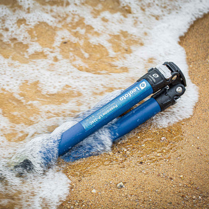 Leofoto LP-324C Poseidon Series water resistant carbon fiber tripod partially submerged in water on a sandy beach